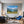 Leinwandbild Alpenlandschaft mit blühenden Wiesen fuer Wohnzimmer blau Querformat